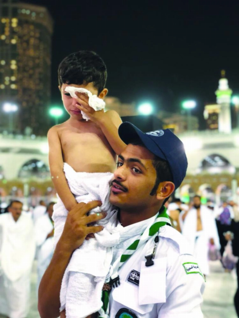 أحد أفراد الكشافة يحمل طفلا تائها (مكة)