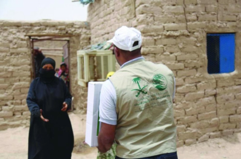 موظف بالمركز يسلم مساعدات لإحدى المستفيدات (واس)