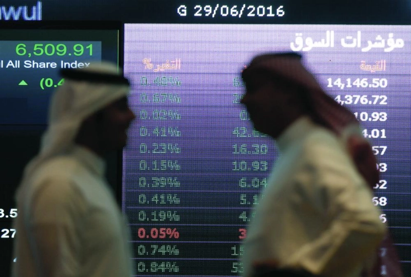 مستثمران يقفان أمام شاشة مؤشرات سوق الأسهم السعودية (مكة)