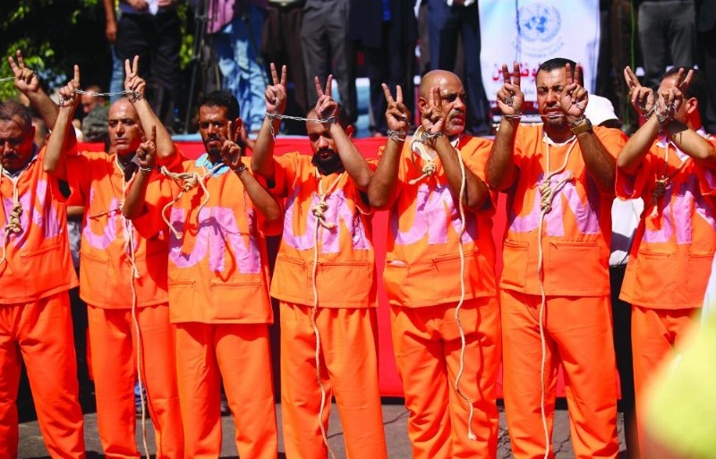 19 September 2018, Palestinian Territories, Gaza: Employees of United Nations Relief and Works Agency (UNRWA) wear orange jumpsuits with hands chained and rope around the neck during a protest against job cuts in front of UNRWA headquarter in Gaza City, Gaza Strip, 19 September 2018. Photo: Dawoud Abo Alkas/APA Images via ZUMA Wire/dpa