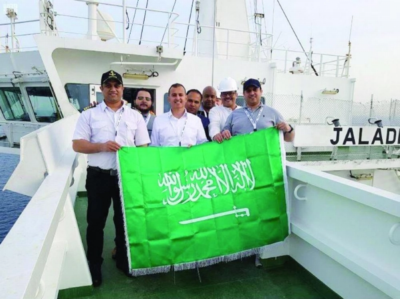 عاملون في النقل البحري يحملون العلم السعودي