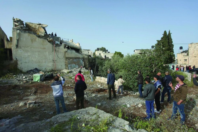 فلسطينيون يقفون بالقرب من منزل عائلة عمر أبوليلى بعد هدمه (د ب أ)