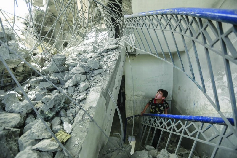 طفل فلسطيني يتفقد الأضرار التي لحقت بمبنى دمر خلال غارات جوية إسرائيلية (د ب أ)