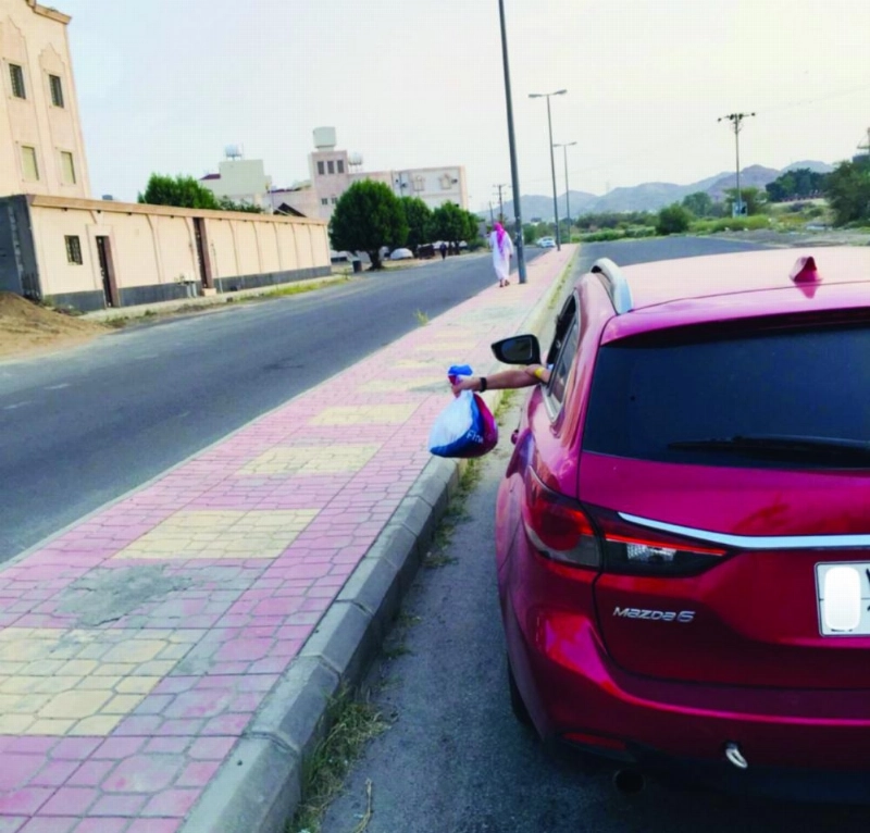 سائق مركبة يلقي بالمخلفات على أحد الأرصفة (مكة)