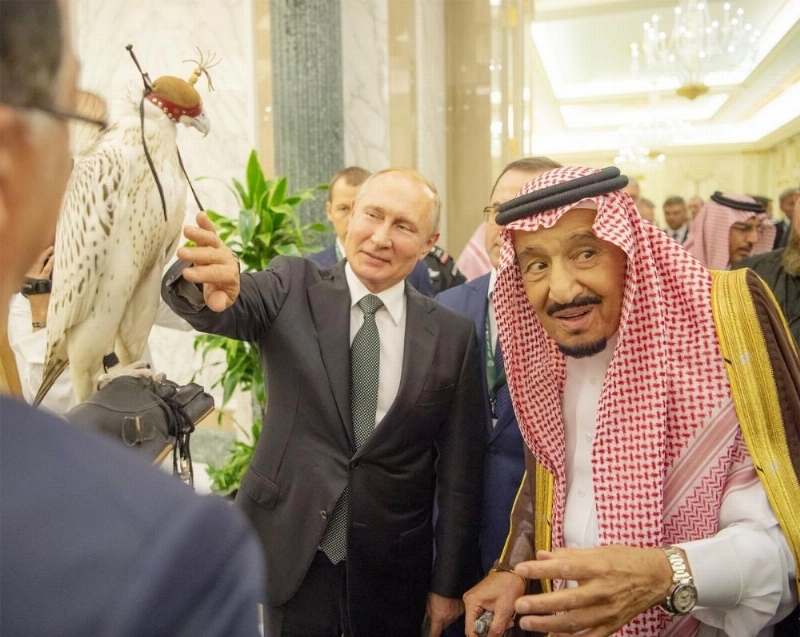 الملك سلمان مطلعا على صقر حر قدمه بوتين هدية له (بندر الجلعود)