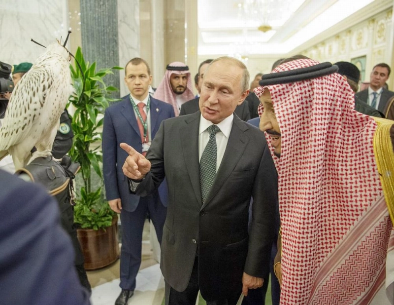 الملك سلمان مطلعا على صقر حر قدمه بوتين هدية له (بندر الجلعود)