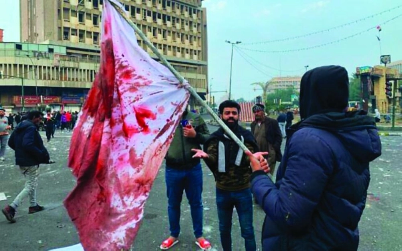 عراقي يحمل علما ملطخا بالدماء تعبيرا عن القتل (مكة)