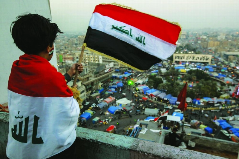 طفل يلوح بالعلم العراقي وهو ينظر إلى ميدان التحرير (د ب أ)