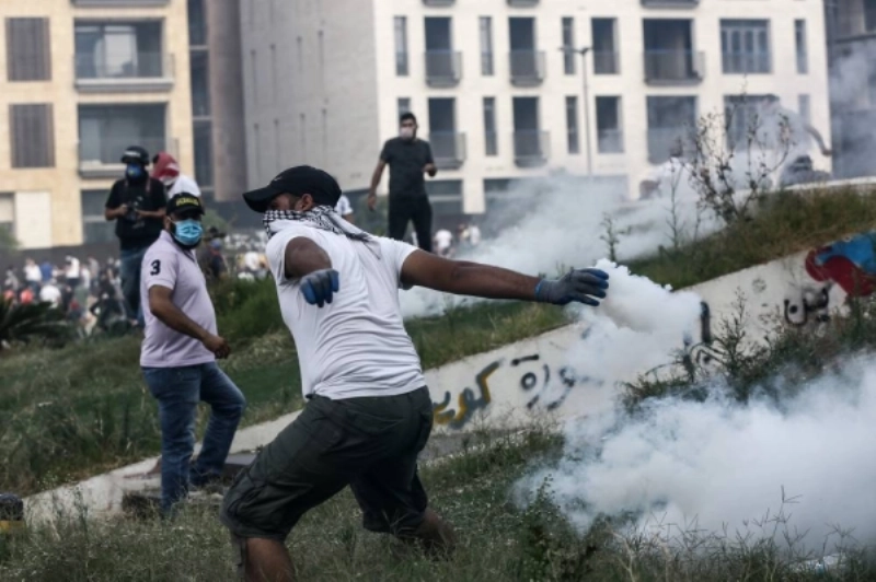 متظاهر يلقي عبوة غاز مسيل للدموع على الشرطة اللبنانية (د ب أ)