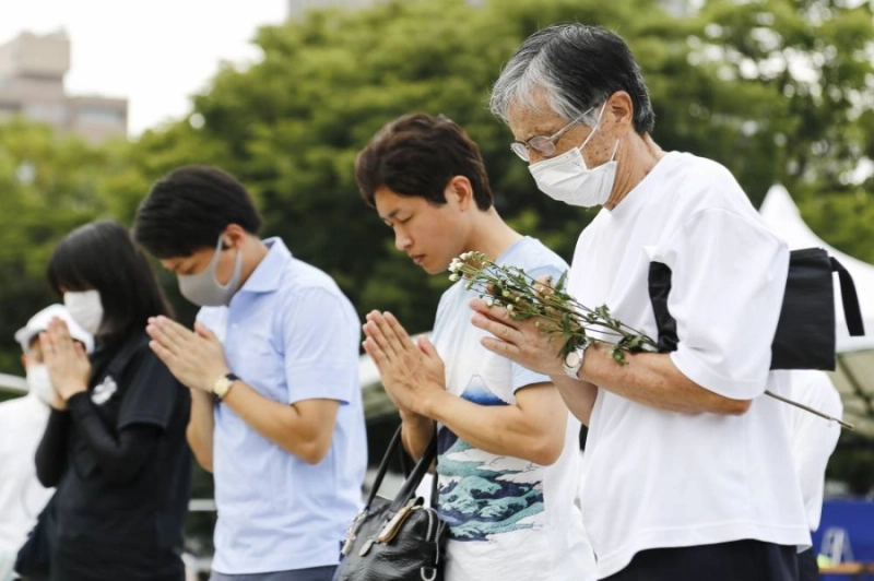 06 August 2020, Japan, Hiroshima: People wearing face masks pray for the atomic bombing victims at the Peace Memorial Park during the annual memorial ceremony to marks the 75th anniversary of the atomic bombing in Hiroshima and Nagasaki by the United States during World War II. Photo: Rodrigo Reyes Marin/ZUMA Wire/dpa