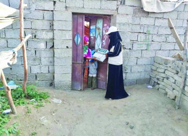 متطوعة توزع كراتين تمور (واس)