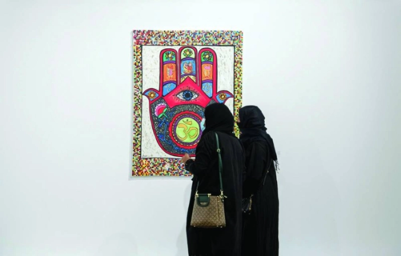 زائرتان تتأملان لوحة فنية بالمعرض