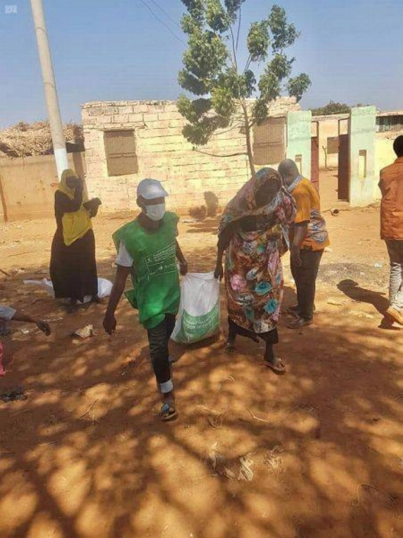 متطوع يساعد سودانية في حمل السلة (واس)