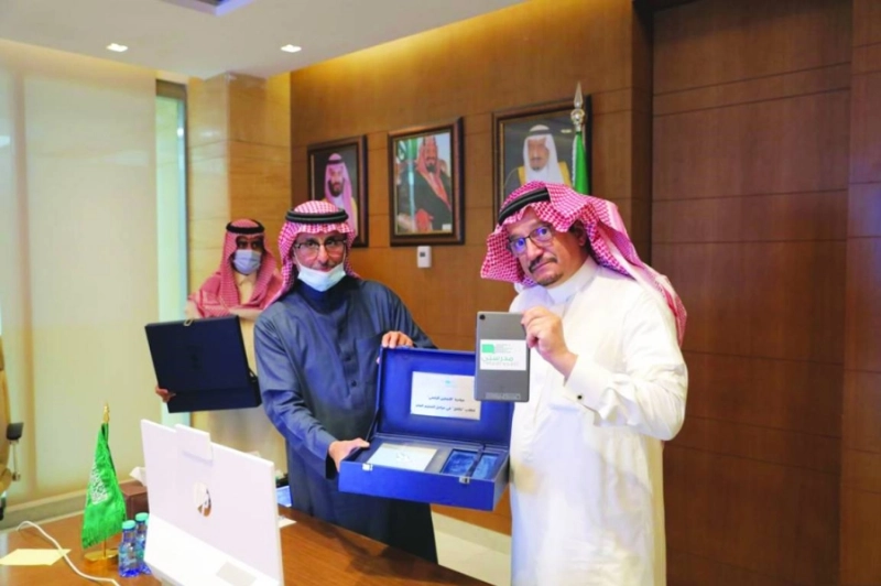 آل الشيخ يحمل جهازا لوحيا خلال التدشين (مكة)