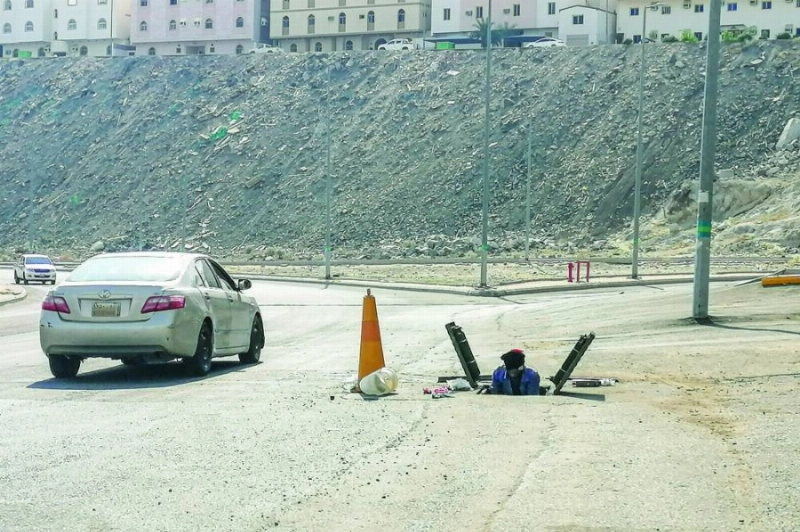 أحد عمال تمديد خطوط الاتصالات خلال تركيب وصيانة التوصيلات بالقرب من أحد الشوارع بحي بطحاء قريش في العاصمة المقدسة، دون توفير وسائل سلامة تحميه من مخاطر السيارات.