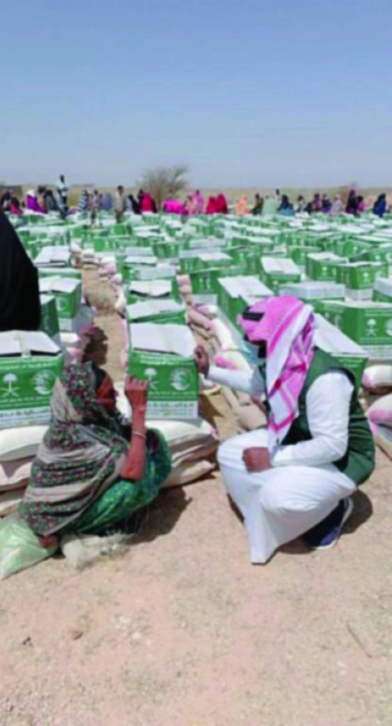 متطوع بالمركز يسلم امرأة صومالية سلة غذائية (واس)