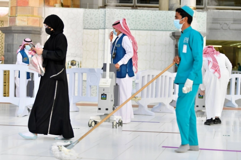 متطوعون خلال التعقيم ودفع عربات المعتمرين في المسجد الحرام (مكة)