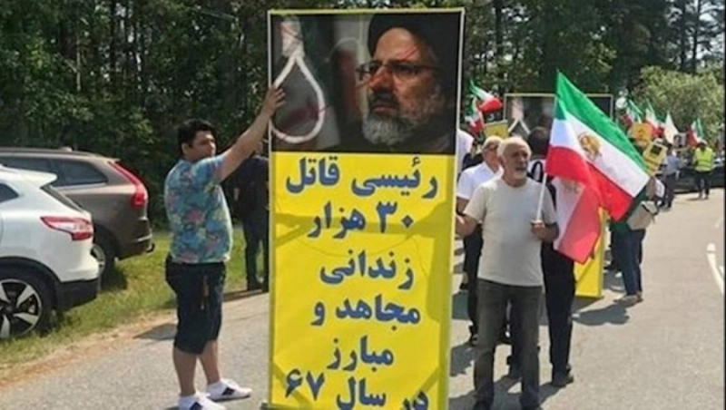 إيرانيون يحملون لافتة مكتوبا عليها «رئيسي قاتل» (مكة)