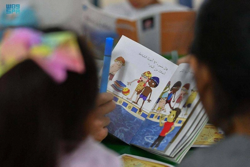 طفلة تتصفح كتابا في المعرض (مكة)