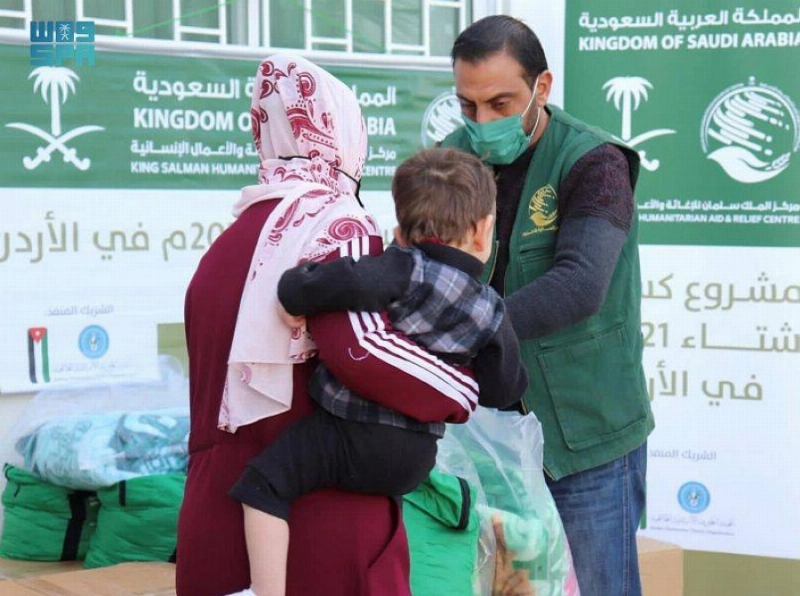 سيدة وطفلها يتسلمان الملابس الشتوية بالأردن (واس)