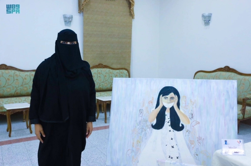 فنانة تشكيلية مع إحدى رسوماتها