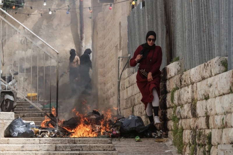 فلسطينية تحاول المرور من نيران تشتعل أمام الأقصى (د ب أ)