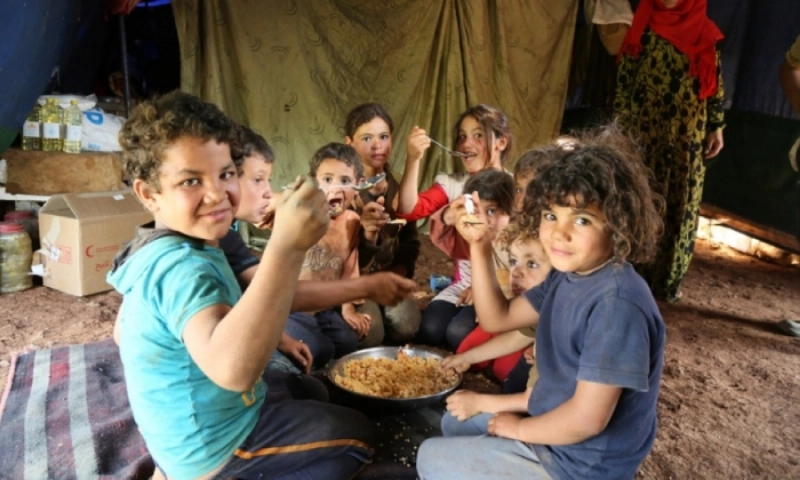 أطفال يتجمعون حول طبق مكرونة