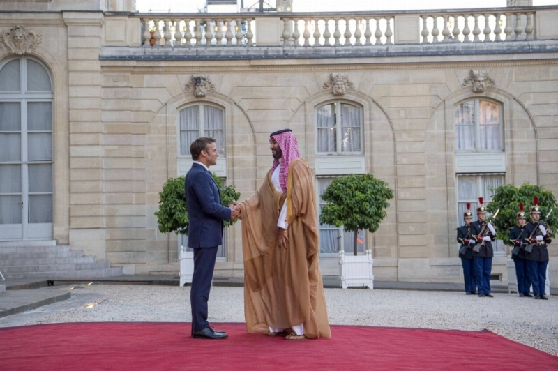 ولي العهد مصافحا الرئيس الفرنسي لدى وصوله إلى قصر الإليزيه في باريس أمس (واس)