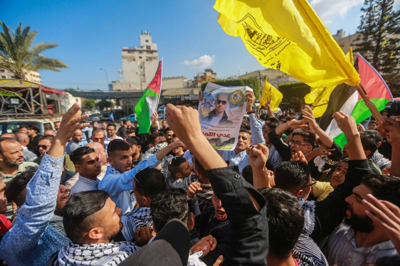 شاب فلسطيني يتظاهر حاملا صور عدي التميمي (د ب أ)