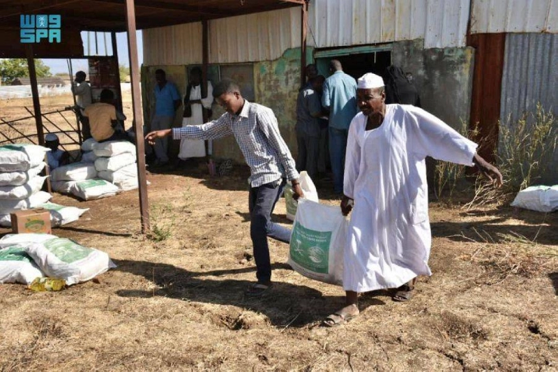سودانيان يحملان سلة من مركز الملك سلمان للإغاثة