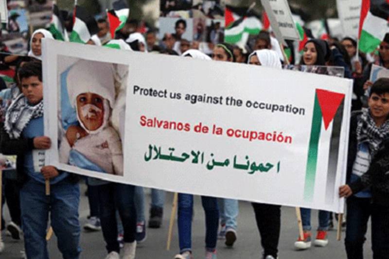 طفل فلسطيني يحمل لافتة ضد الاحتلال (مكة)