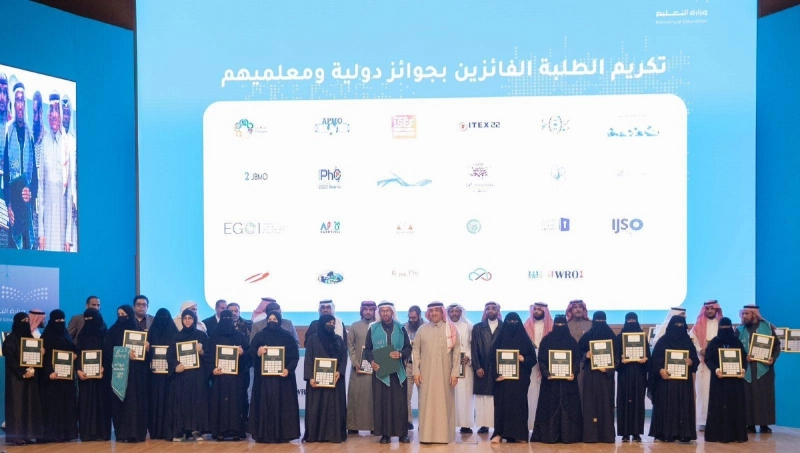 يوسف البنيان يتوسط المعلمين والمعلمات خلال التكريم