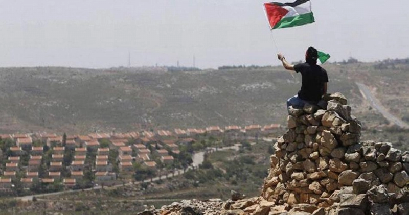 فلسطيني يرفع علم بلده في الضغة الغربية (مكة)