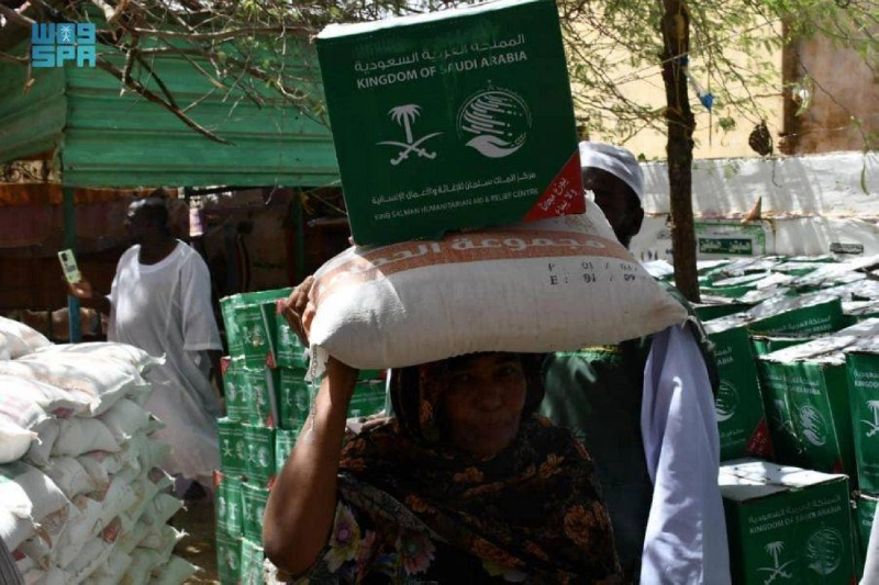 سودانية تحمل المواد الغذائية من مركز الملك سلمان للإغاثة (واس)