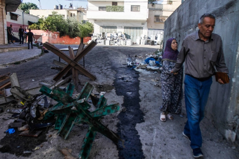 فلسطينيون يسيرون في وسط مخيم جنين