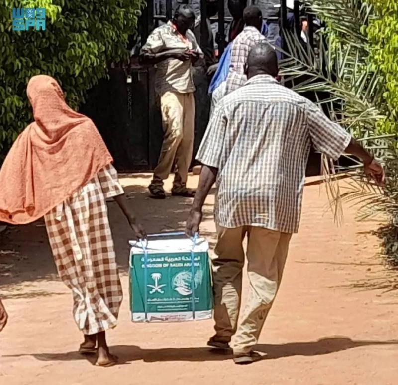 سودانيان يحملان مساعدات مركز الملك سلمان للإغاثة عملية جراحية سعودية في بورتسودان (واس)