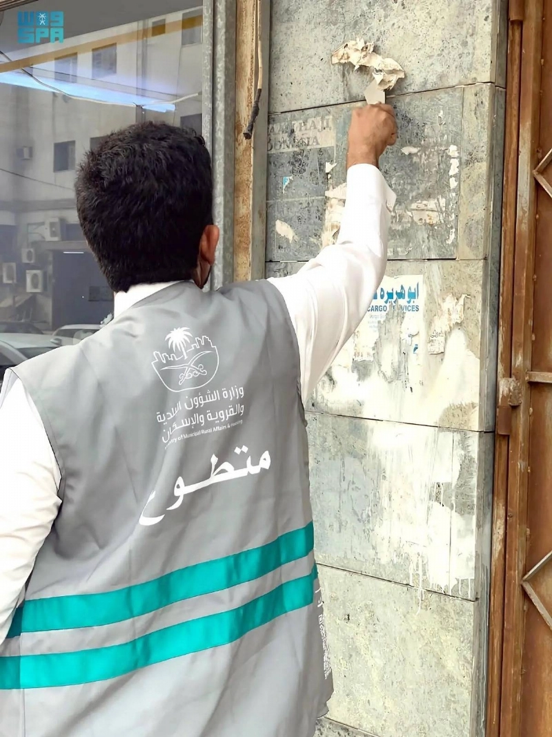 متطوع يزيل ملصقات عشوائية (مكة)