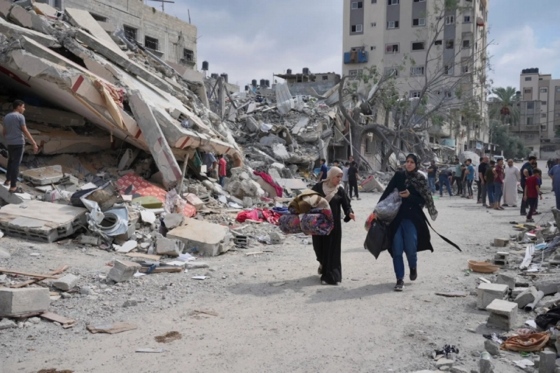 فلسطينيات تسير بجوار مباني دمرها الاحتلال (مكة)