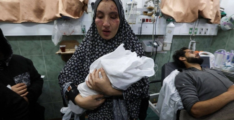 سيدة فلسطينية مصابة تحمل طفلها حديث الولادة