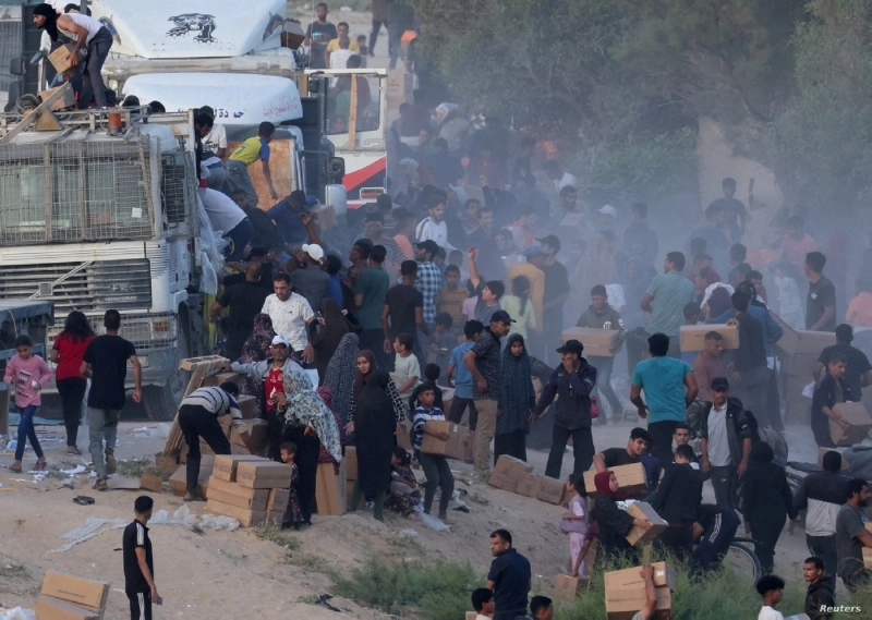 فلسطينيون يصعدون لإحدى الشاحنات للحصول على المساعدات (مكة)