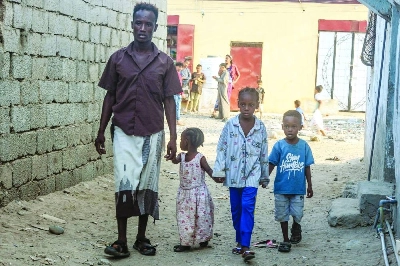 Photo taken on October 23, 2025 shows Somali refugee Abdullah Omar walk with his children along an alleyway as they wait for news of their repatriation from Yemen, in Aden. Photo taken on October 23, 2025 shows Somali refugee Abdullah Omar walk with his children along an alleyway as they wait for news of their repatriation from Yemen, in Aden.