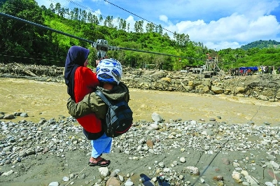 People use a rope to cross a river in the aftermath of flash floods that destroyed adjacent villages in Ketol, Indonesia’s Aceh highland province, Tuesday. People use a rope to cross a river in the aftermath of flash floods that destroyed adjacent villages in Ketol, Indonesia’s Aceh highland province, Tuesday.