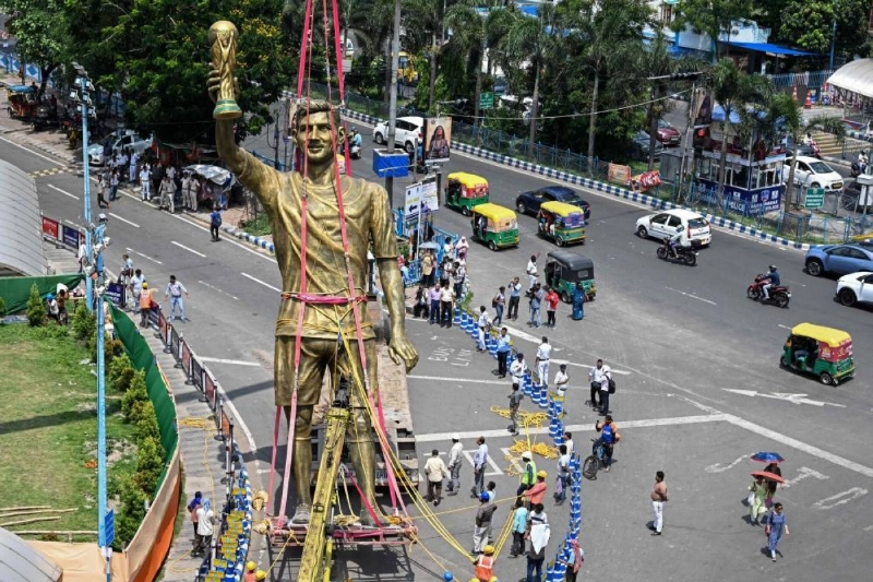 Pedestrians watch as workers remove a statue of Argentine football player Lionel Messi for its re-installation to a safer place in Kolkata yesterday. (AFP) Pedestrians watch as workers remove a statue of Argentine football player Lionel Messi for its re-installation to a safer place in Kolkata yesterday. (AFP)