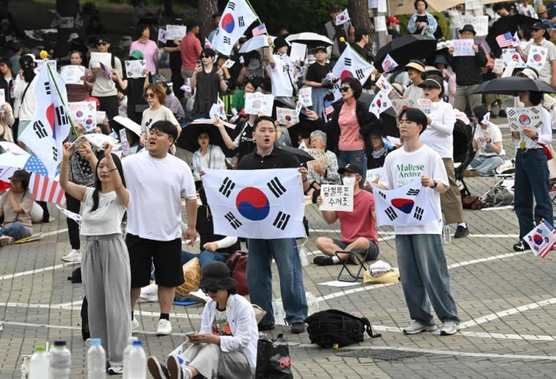 Korean protesters wave the national flags outside a vote-counting centre in Seoul Wednesday, to call for a rerun of the local elections due to a shortage of ballot papers. (AFP) Korean protesters wave the national flags outside a vote-counting centre in Seoul Wednesday, to call for a rerun of the local elections due to a shortage of ballot papers. (AFP)