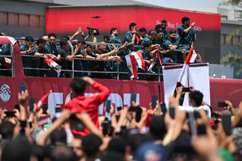 Fans cheer on Egypt's players as they ride atop an open-top bus after they have arrived at El-Alamein International Airport in the northern coastal city of El-Alamein on July 10, 2026, following their participation in the FIFA World Cup. (AFP) Fans cheer on Egypt's players as they ride atop an open-top bus after they have arrived at El-Alamein International Airport in the northern coastal city of El-Alamein on July 10, 2026, following their participation in the FIFA World Cup. (AFP)