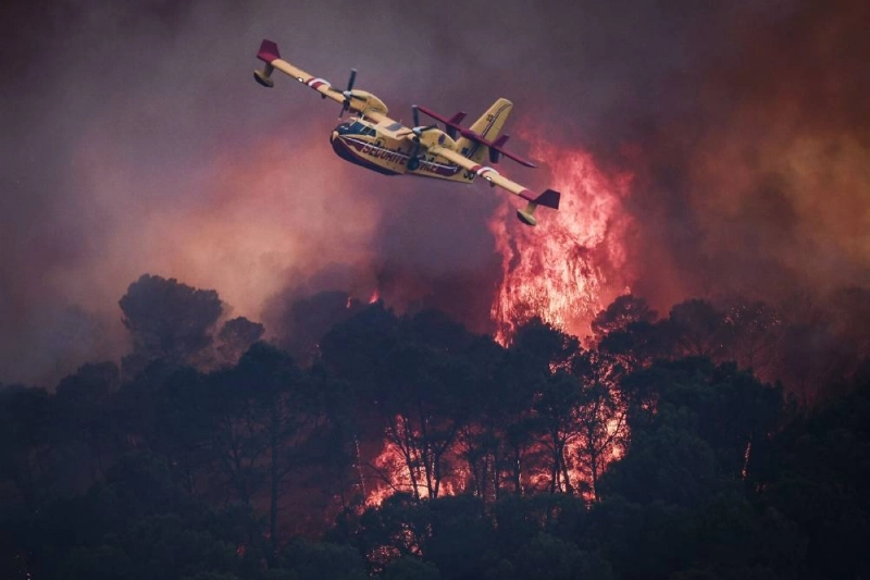 A French Civil Security Canadair CL-415 aircraft flies past flames burning a forest surrounding Cotignac, southeastern France yesterday during a wildfire. (AFP) A French Civil Security Canadair CL-415 aircraft flies past flames burning a forest surrounding Cotignac, southeastern France yesterday during a wildfire. (AFP)