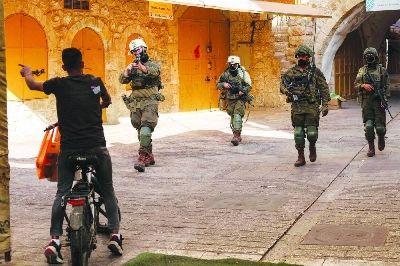 Israeli soldiers warn a man on a scooter to leave as Palestinians are evacuated Saturday from the market in the old city of Hebron while Israeli settlers tour the area. AFP Israeli soldiers warn a man on a scooter to leave as Palestinians are evacuated Saturday from the market in the old city of Hebron while Israeli settlers tour the area. AFP
