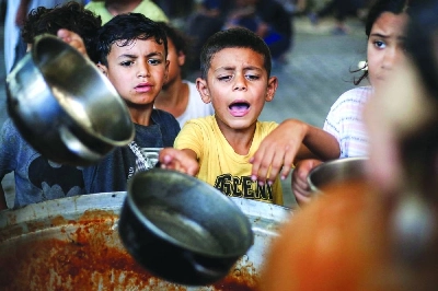 Children receive meals from a charity kitchen at the Maghazi camp for Palestinian refugees in the central Gaza Strip. (AFP)
Children receive meals from a charity kitchen at the Maghazi camp for Palestinian refugees in the central Gaza Strip. (AFP)
