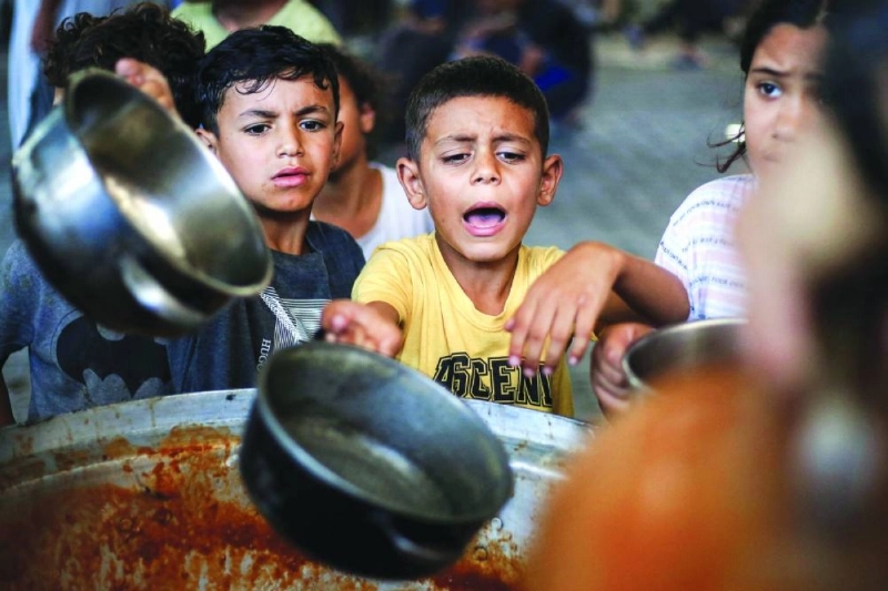 Children receive meals from a charity kitchen at the Maghazi camp for Palestinian refugees in the central Gaza Strip. (AFP)
Children receive meals from a charity kitchen at the Maghazi camp for Palestinian refugees in the central Gaza Strip. (AFP)