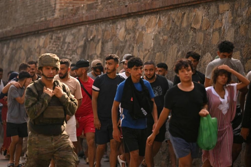 A Spanish soldier escorts a group of migrants on their way back towards the Moroccan border, following their illegal crossing into the Spanish enclave of Ceuta, on August 1, 2026. (Photo by JORGE GUERRERO / AFP) A Spanish soldier escorts a group of migrants on their way back towards the Moroccan border, following their illegal crossing into the Spanish enclave of Ceuta, on August 1, 2026. (Photo by JORGE GUERRERO / AFP)
